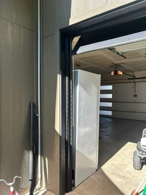 View of a garage doorway with a refrigerator and clean interior space.
