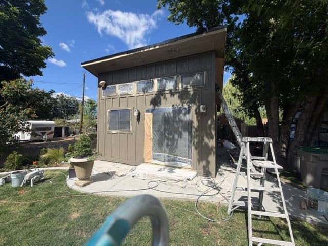 Exterior of a house being painted, showing scaffolding and preparation for work.
