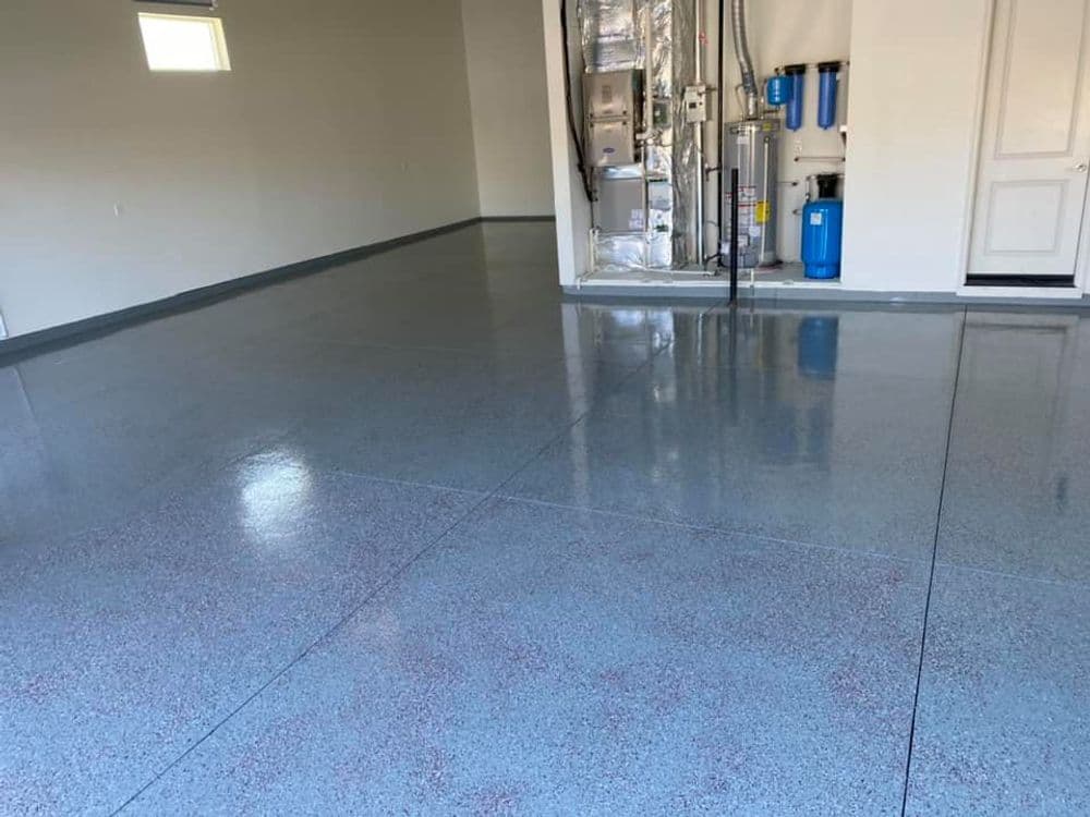 Shiny epoxy garage floor with storage area and equipment in the background.