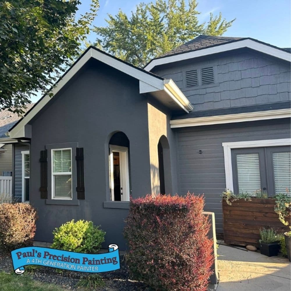Exterior of a home painted in gray with blue accents, featuring a well-maintained garden.