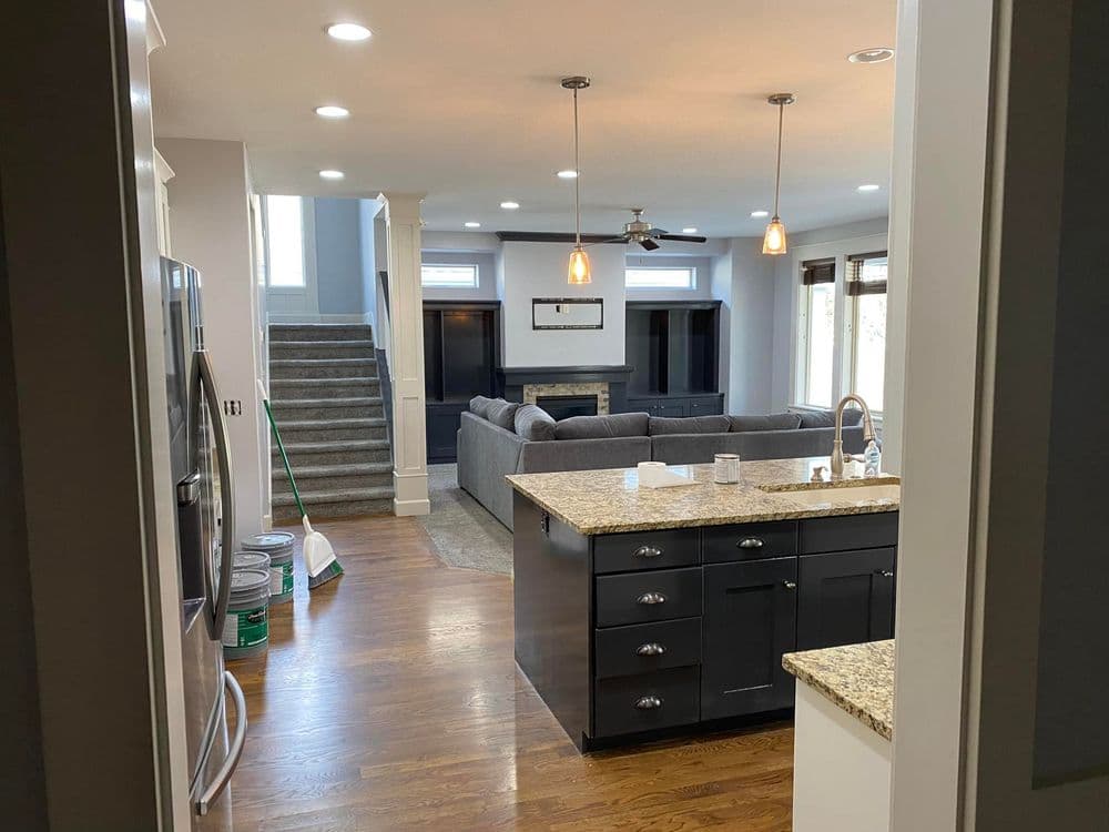 Modern kitchen with granite countertops overlooking a spacious living room and staircase.