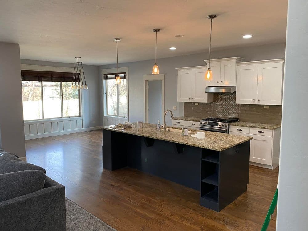 Modern kitchen with granite island, pendant lights, and hardwood flooring, featuring a spacious layout.