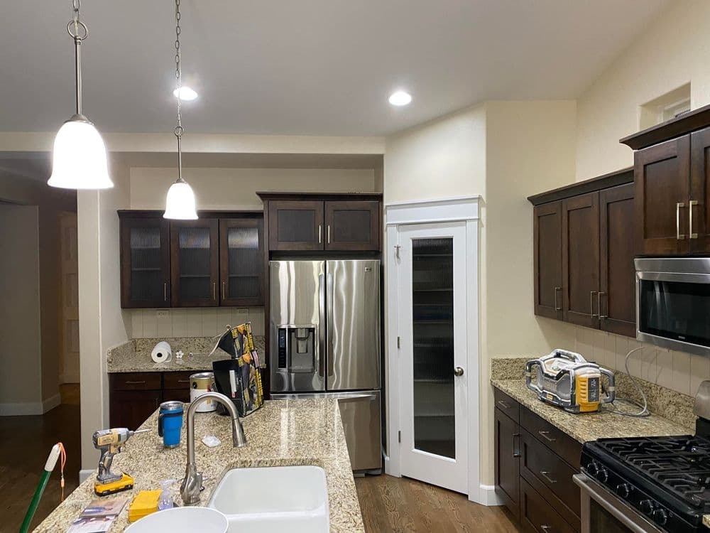 Modern kitchen with dark wood cabinets, granite countertops, stainless steel appliances, and bright lighting.