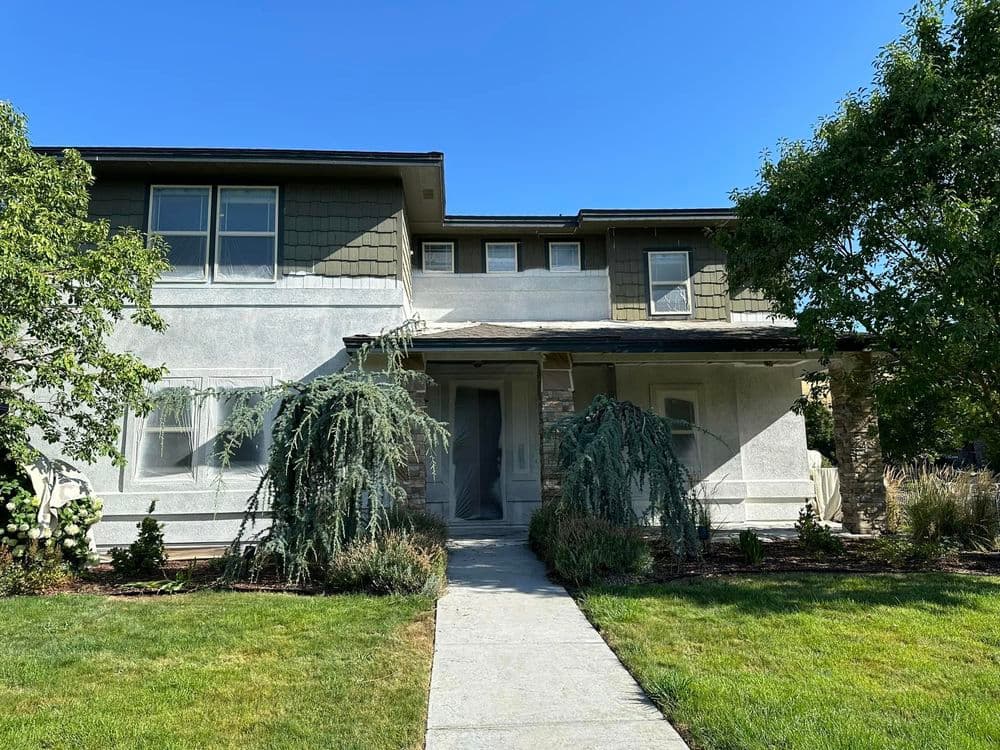 Two-story home with a landscaped front yard and clear blue sky.