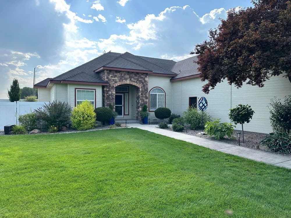 Beautiful home exterior with lush green lawn, stone accents, and landscaped garden.