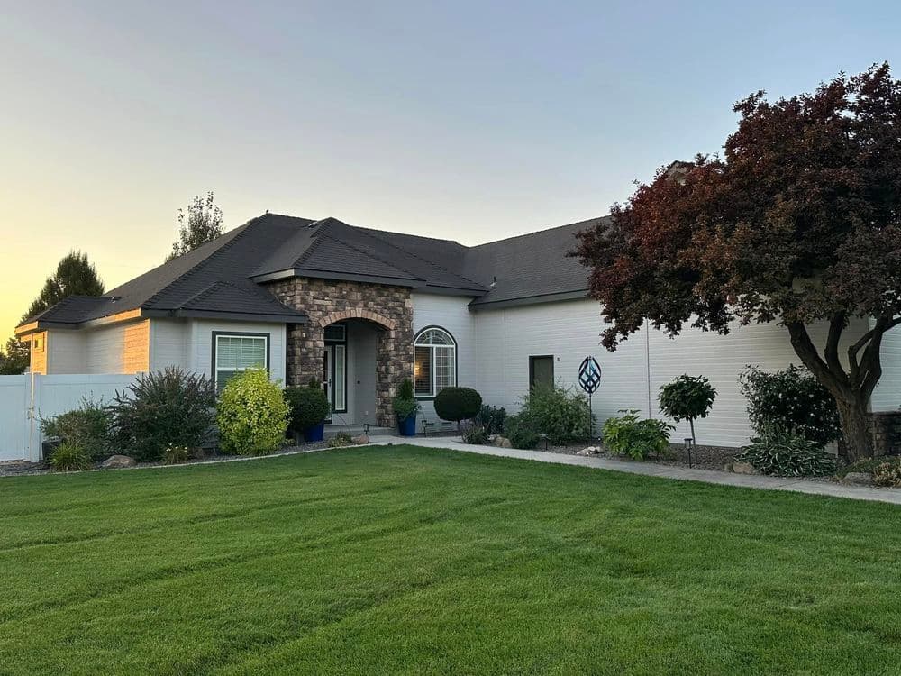 Charming suburban home with stone accents, landscaped yard, and sunset backdrop.