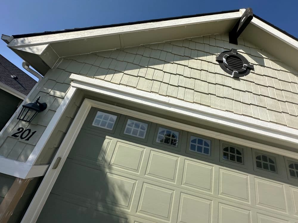Exterior of a house featuring a green garage door, decorative vent, and house number 201.