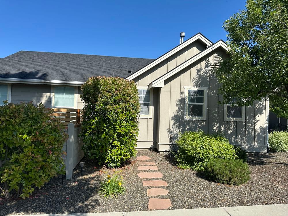 Charming suburban home with landscaped garden and stone pathway under clear blue sky.